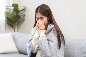 Sick, coronavirus or covid, tired asian young woman have a fever, flu and hand in use tissues paper sneezing nose, runny while sitting on sofa, couch at home. Health care with disease, pandemic virus