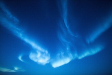 Fototapeta premium wispy blue clouds, ethereal atmosphere, cirrus clouds, bioluminescent glow, dreamlike celestial scene, deep blue background, whispy cloud formations, surreal skyscape, mystical ambiance.