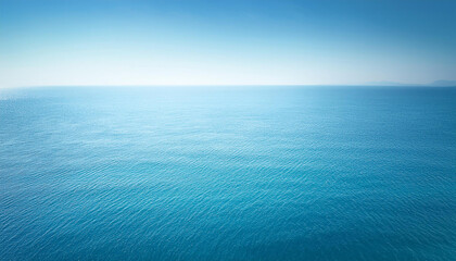 Obraz premium A serene and tranquil seascape of a calm ocean meeting a clear blue sky. The water is a crystal-clear turquoise color, and the surface is gently rippled by a soft breeze.