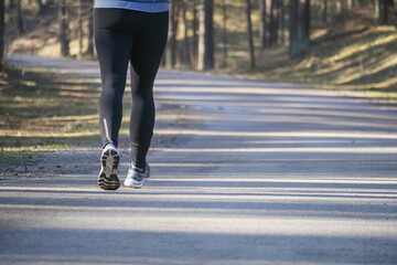 
A man in sportswear running on a forest path.