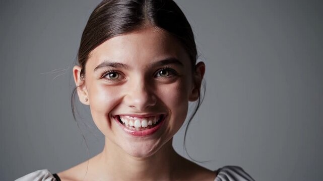 Young girl with beautiful smile on grey background. Teeth whitening