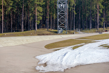 
Track with snow cover, wooden construction tower in background and forest.