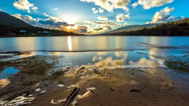 Sun in the clouds reflected in the water of the ocean on Nubeena Road, in the Tasman Peninsula in the south eastern coast of Tasmania, Australia. REAL PHOTO animated by AI