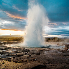 Strokkur geysir erupting with hot water and steam at sunrise in south Iceland...