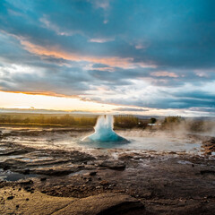 Strokkur geysir erupting with hot water and steam at sunrise in south Iceland...