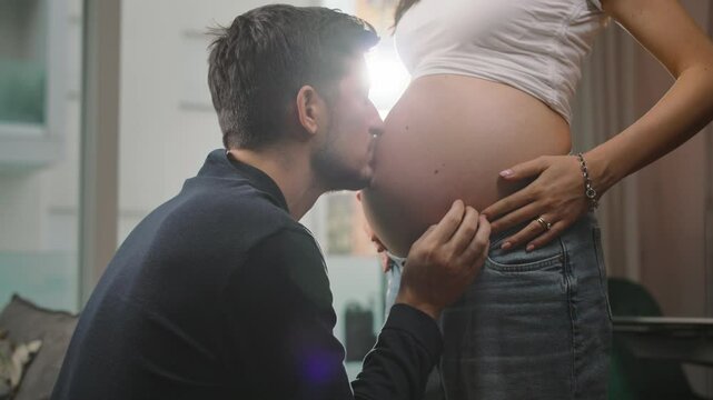 Expecting father tenderly kissing his pregnant wife's belly, capturing the intimate and loving anticipation of welcoming their new baby into the world