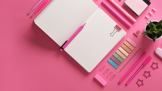 Horizontal stationery background with open notebook with stationery in pink theme.