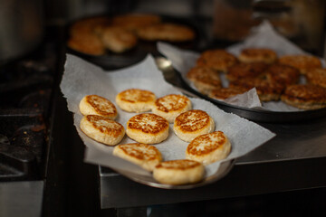 Delicious syrniki cooling on baking paper after being cooked on a pan in a professional kitchen