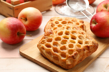 Delicious puff pastries with apples on white wooden table, closeup