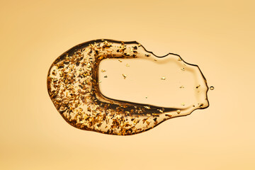 A delicious drop of 24k gold serum on a gold background.