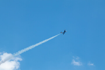 Aero L-29 Delfín jet plane with contrail on cloudy blue sky background on airshow