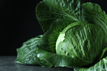 Obraz premium Whole ripe head of cabbage on table against dark background, closeup