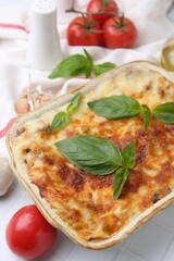 Delicious cooked lasagna with basil served on white table, closeup