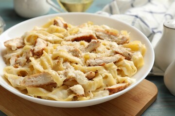 Tasty Alfredo pasta with chicken on light blue wooden table, closeup