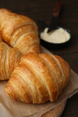 Tasty fresh croissants served with butter on wooden table, closeup