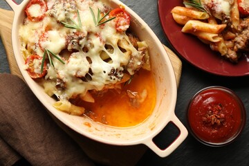 Flat lay composition with delicious pasta casserole on dark textured table