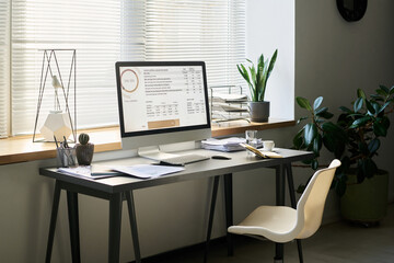 Workplace of modern analyst with desktop computer and keypad, financial paper documents, open notebook and other stationary