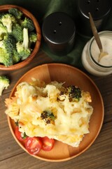 Tasty pasta casserole with cheese and broccoli served on wooden table, flat lay