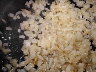 Sizzling onions caramelize in a hot skillet, releasing their rich aroma and transforming into a golden delight at a cozy home kitchen