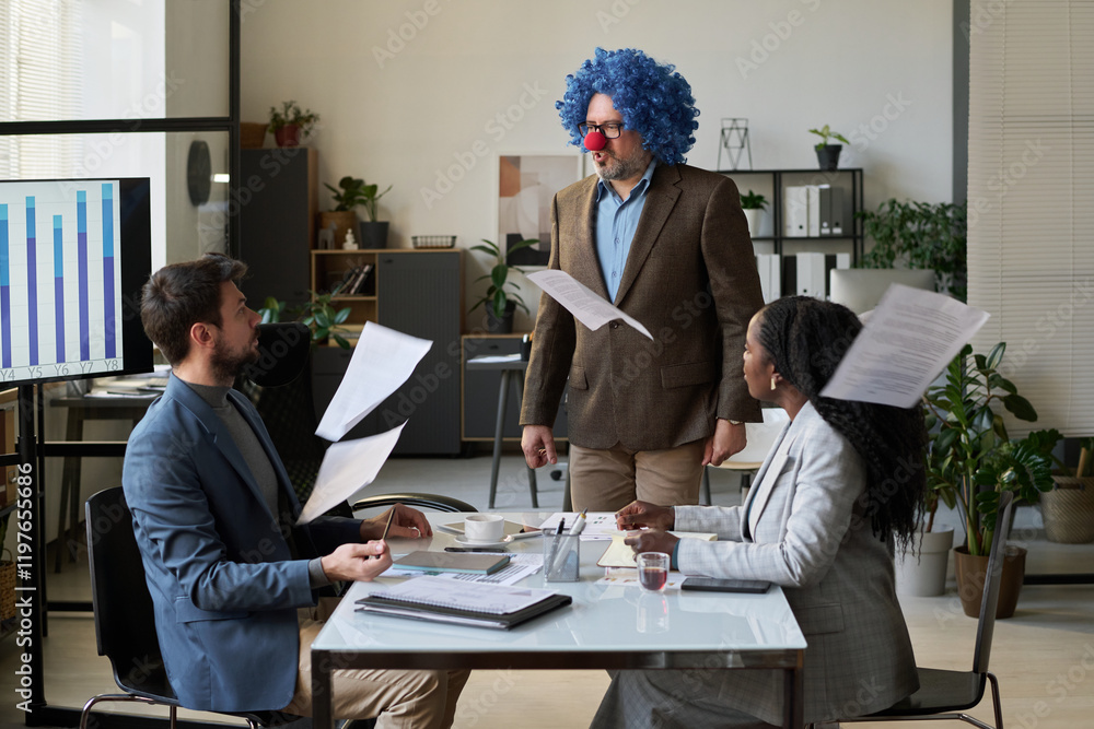 Poster annoyed male boss in clown wig and nose standing in front of his subordinates while paper documents 