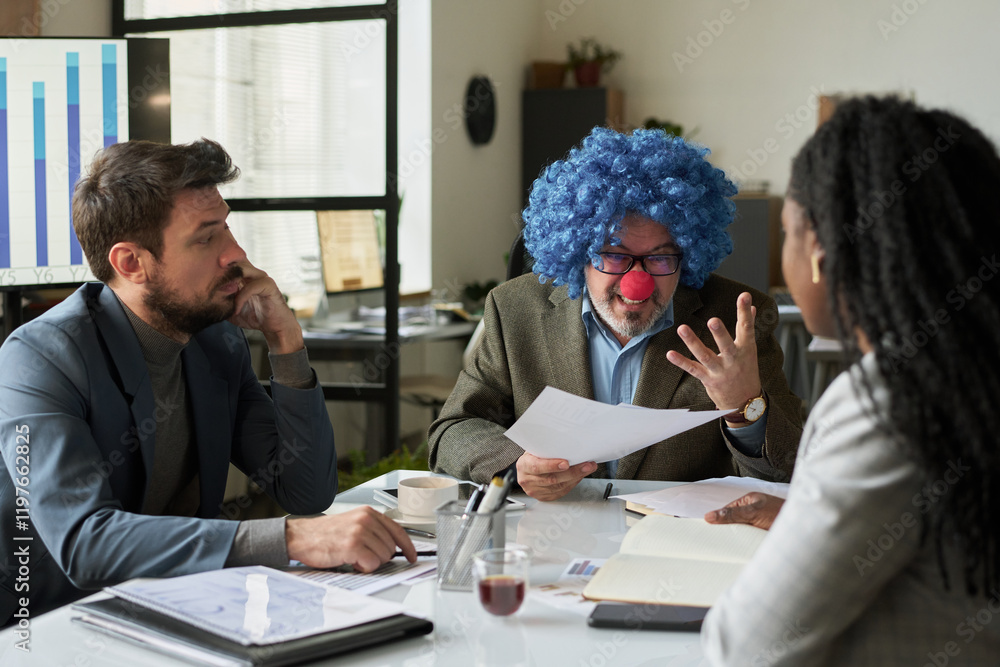 Poster Smiling boss in clown wig looking at one of young subordinates at meeting while explaining points of financial documents