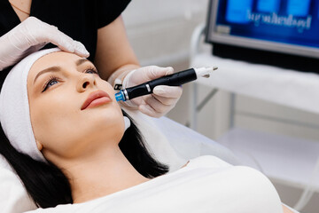 A cosmetologist performing a hydrafacial on a woman's face in a beauty clinic. Concept of...