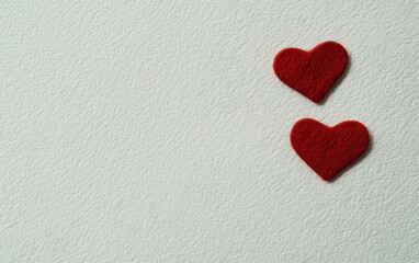 Obraz premium Two vibrant red hearts rest gently on a pristine white surface, symbolizing love and affection in a serene and romantic setting.