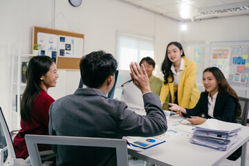 Asian businesspeople are discussing work and sharing ideas in a meeting room, collaborating on a project and analyzing financial charts and documents