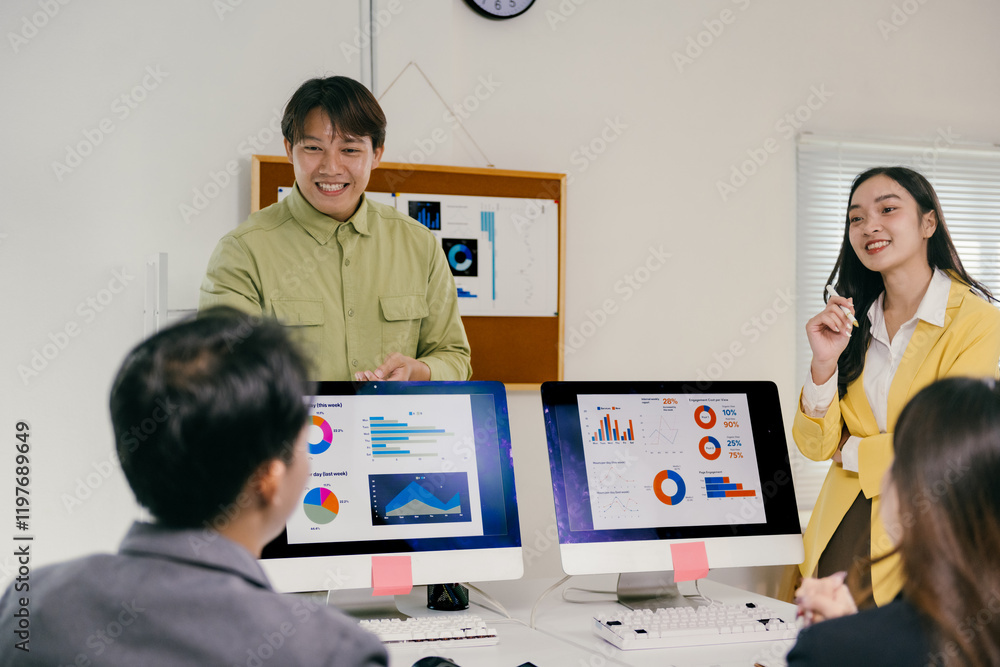 Aufkleber two asian marketing managers presenting infographic data on computer screens to colleagues during a 
