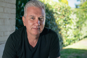 Portrait of a self-confident senior man in the garden of his house.