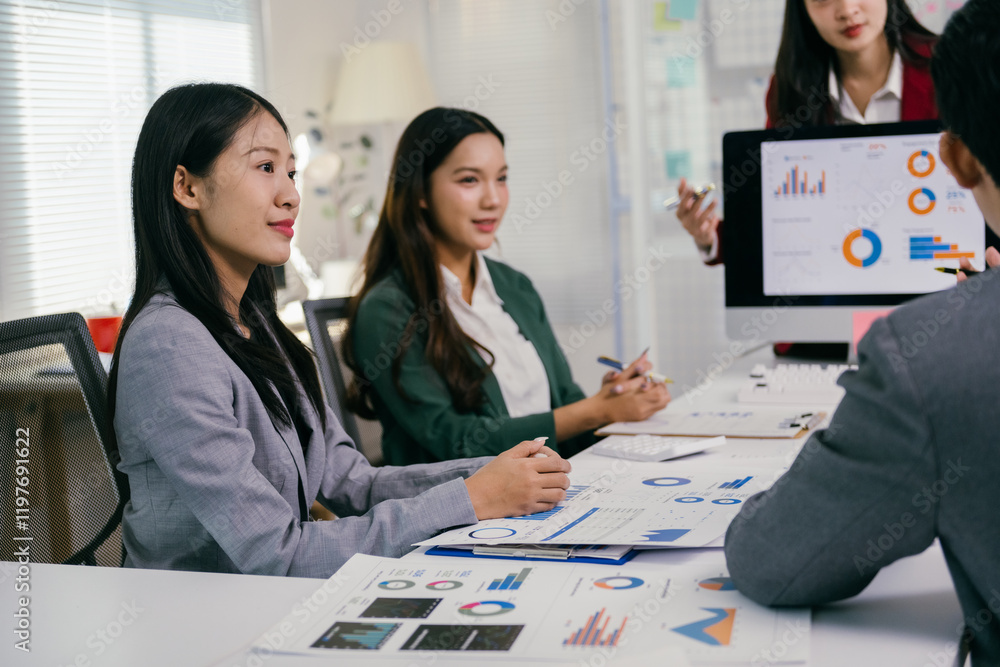 Poster asian businesswomen attending a presentation about financial charts and data displayed on a computer