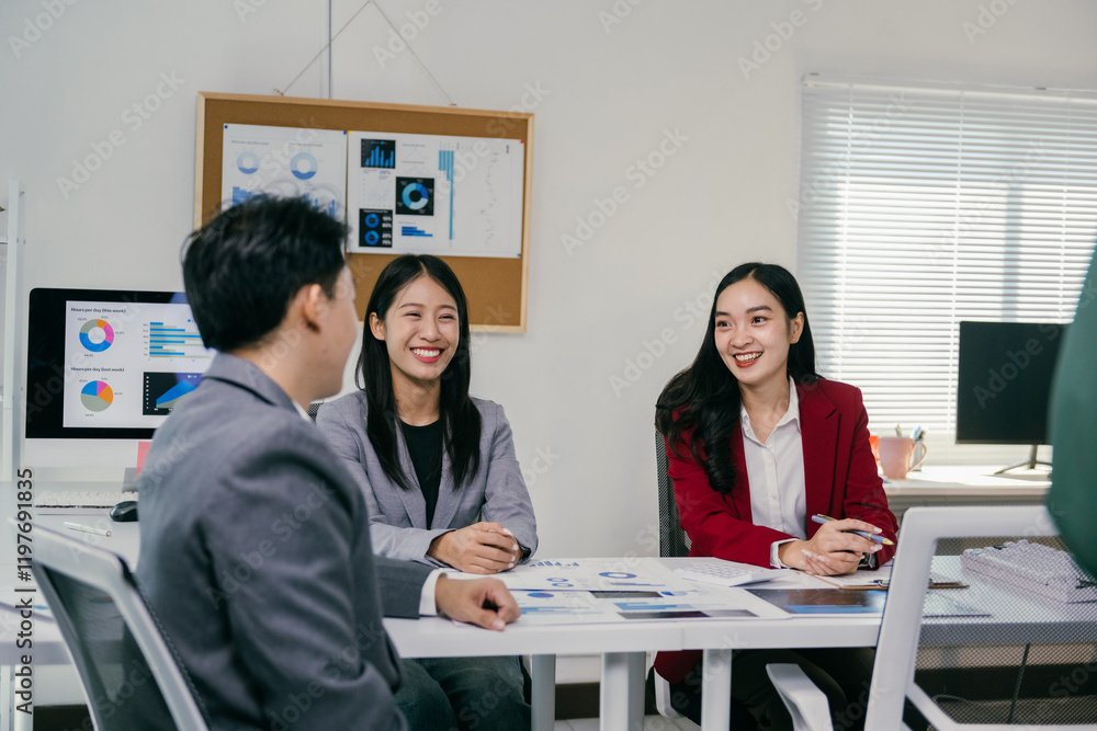Poster three asian businesspeople are sitting at a table, smiling and discussing business during a meeting 