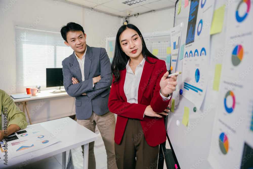 Poster young professional businesswoman explaining charts and diagrams on whiteboard during a productive me