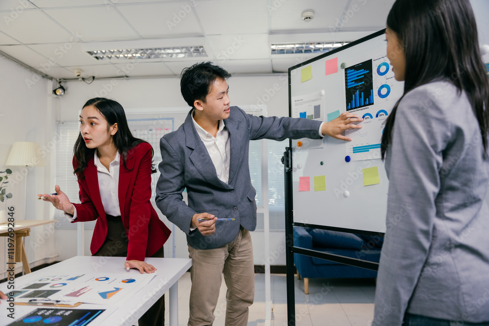 Poster Group of young asian businesspeople analyzing charts and graphs on a whiteboard and table, discussing strategies and collaborating in a modern office environment