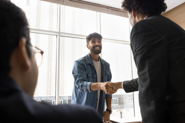 Two positive Arabian businessmen shaking hands, standing at conference table, start or finalize...