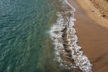 Aerial Drone shot showing the wave breaks on the golden coloured sand beach