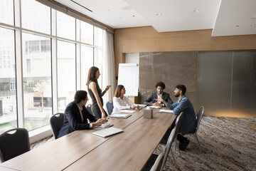 Young attractive European business coach hold training for staff members, gathered in modern...
