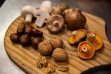 Bodegón de frutos secos, nueces, castañas, setas, hojas sobre encimera madera