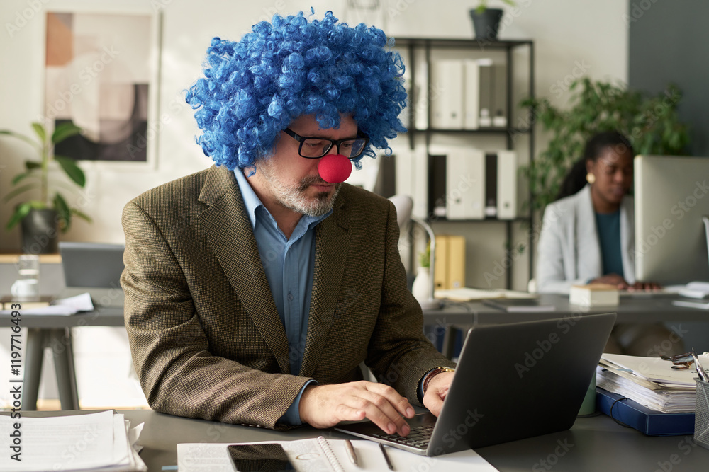 Poster mature clown director of business company looking at laptop screen and typing while organizing work 