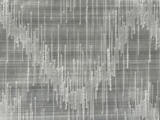 Close up of sewn nylon fabric with arrow chevron V shape pattern in shades of transparent white...