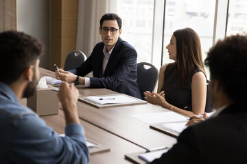 Group of serious professional businesspeople solve business-related issue or challenges gathered in...
