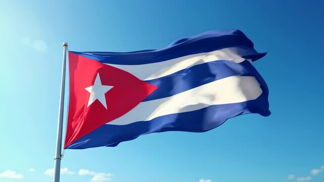 Brightly colored Cuban flag billows in the wind under a clear blue sky, symbolizing national pride and identity.