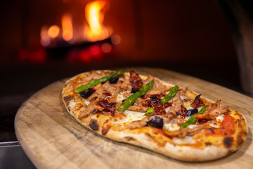 Pizza entrando o saliendo de horno de leña