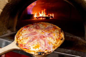 Pizza entrando o saliendo de horno de leña