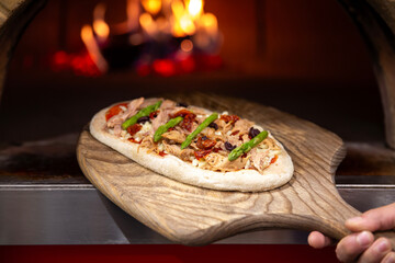 Pizza entrando o saliendo de horno de leña
