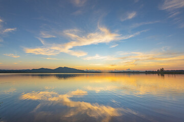 Landscape of mountains and lake at sunset and clouds reflected in the water.