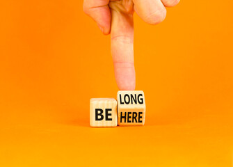 Belonging and belong symbol. Concept words Be here Belong on beautiful wooden block. Beautiful orange background Businessman hand. Business motivational belonging and belong concept. Copy space.