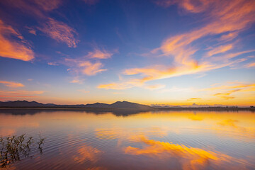Obraz premium Landscape of mountains and lake at sunset and clouds reflected in the water.