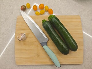 Fresh zucchini and cherry tomatoes await culinary creation on a wooden cutting board in a modern kitchen