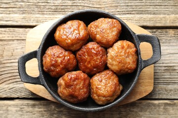 Tasty meatballs in baking dish on wooden table, top view